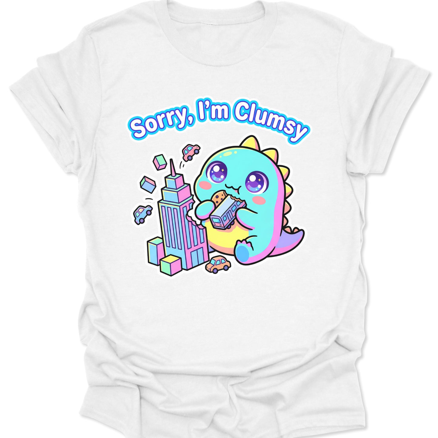 White unisex adult t-shirt featuring a pastel chibi kaiju eating a bus with "Sorry, I'm Clumsy" text in bubbly letters.