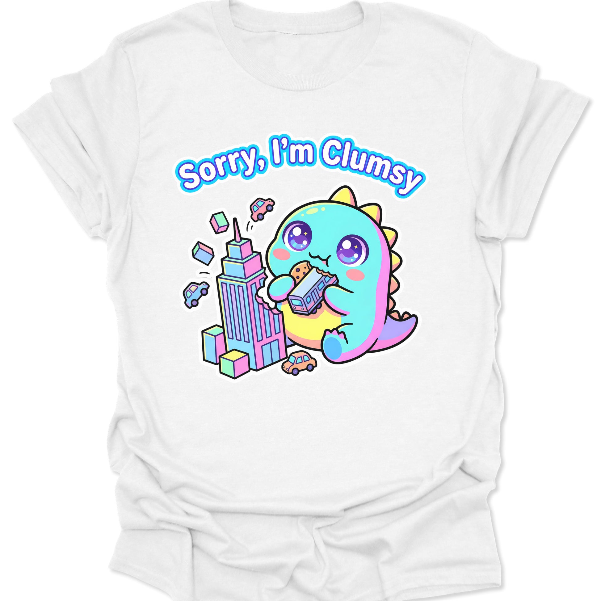White unisex adult t-shirt featuring a pastel chibi kaiju eating a bus with "Sorry, I'm Clumsy" text in bubbly letters.