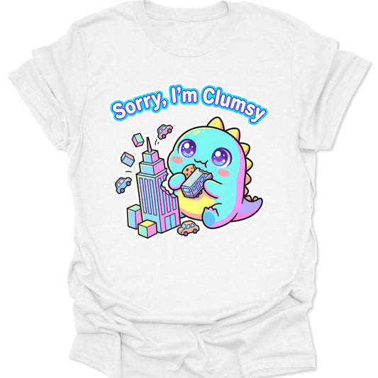 White unisex adult t-shirt featuring a pastel chibi kaiju eating a bus with "Sorry, I'm Clumsy" text in bubbly letters.