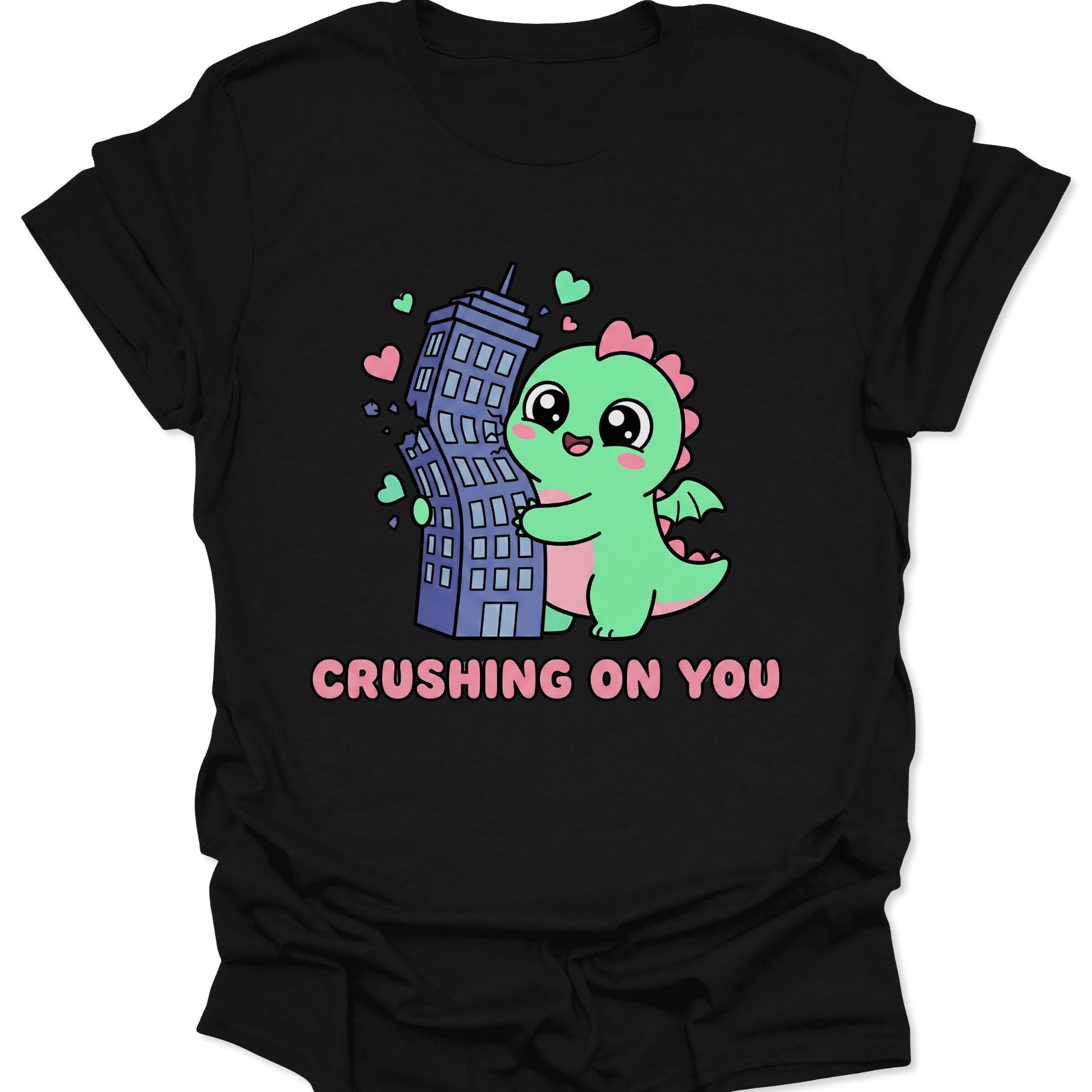 Black unisex adult t-shirt featuring a cute green kaiju hugging a skyscraper with pink hearts and Crushing On You text.