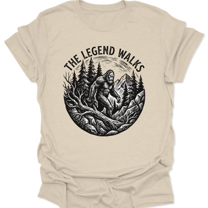 Natural unisex adult t-shirt featuring a hand-drawn legend walks cryptid design with tall evergreen trees and peaks.