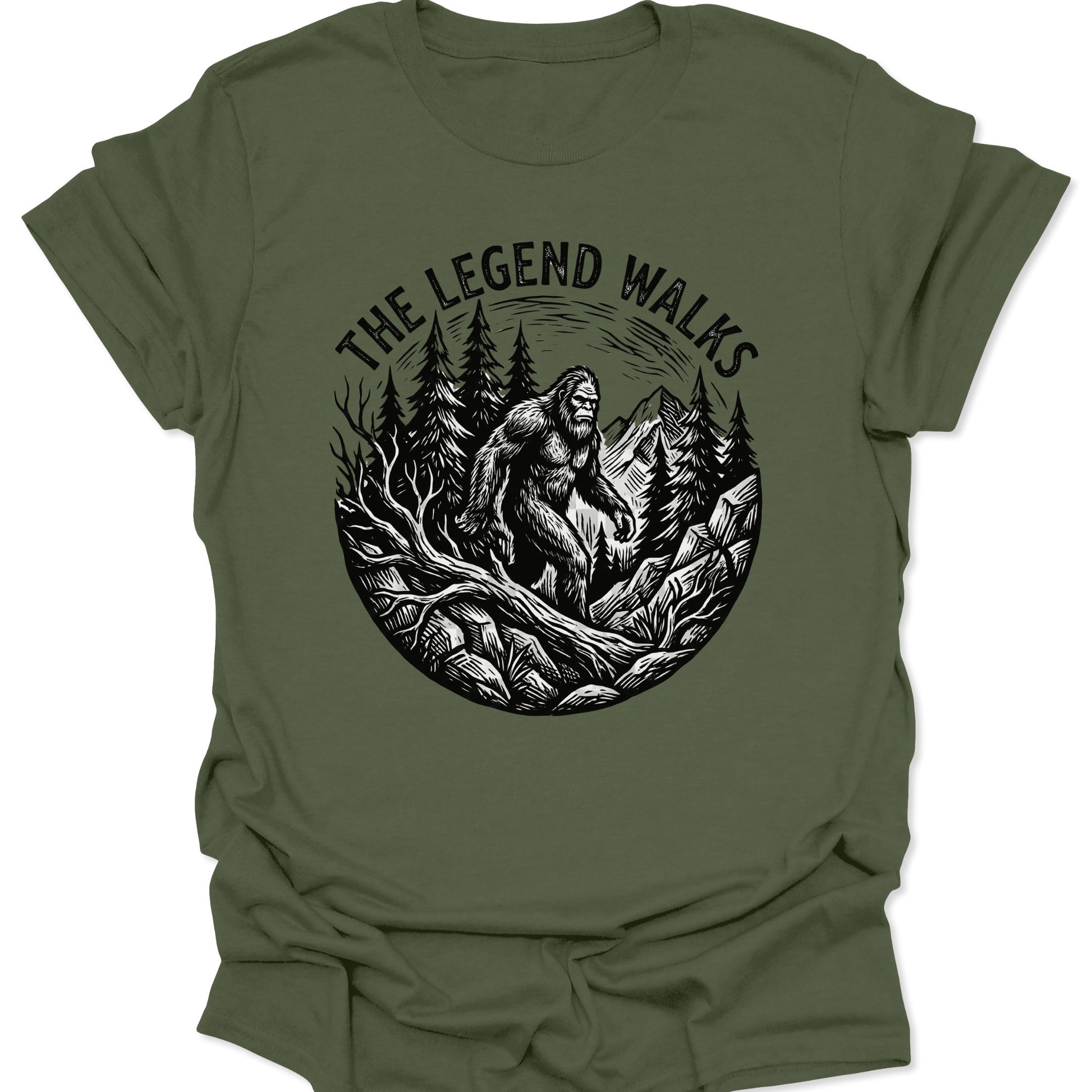 Military Green unisex adult t-shirt featuring a rugged Sasquatch hiking graphic in a high-contrast mountain landscape.