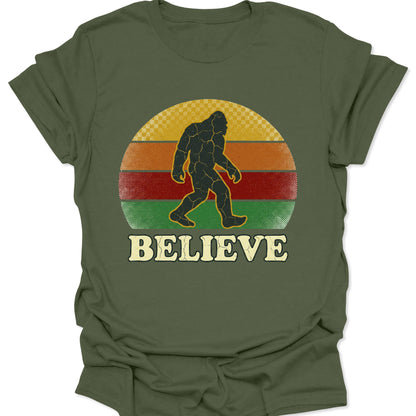 Military green unisex adult t-shirt featuring a retro cryptid hunter design with Bigfoot and bold Believe text.