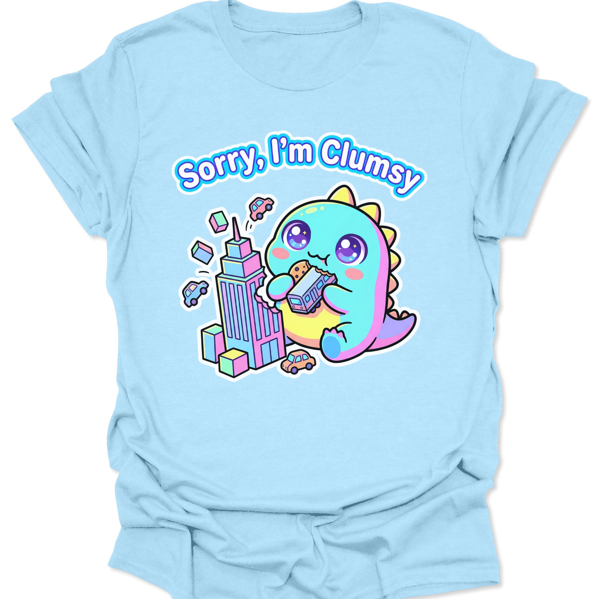 Light Blue unisex t-shirt featuring a pastel chibi kaiju eating a bus with "Sorry, I'm Clumsy" text in bubbly letters.