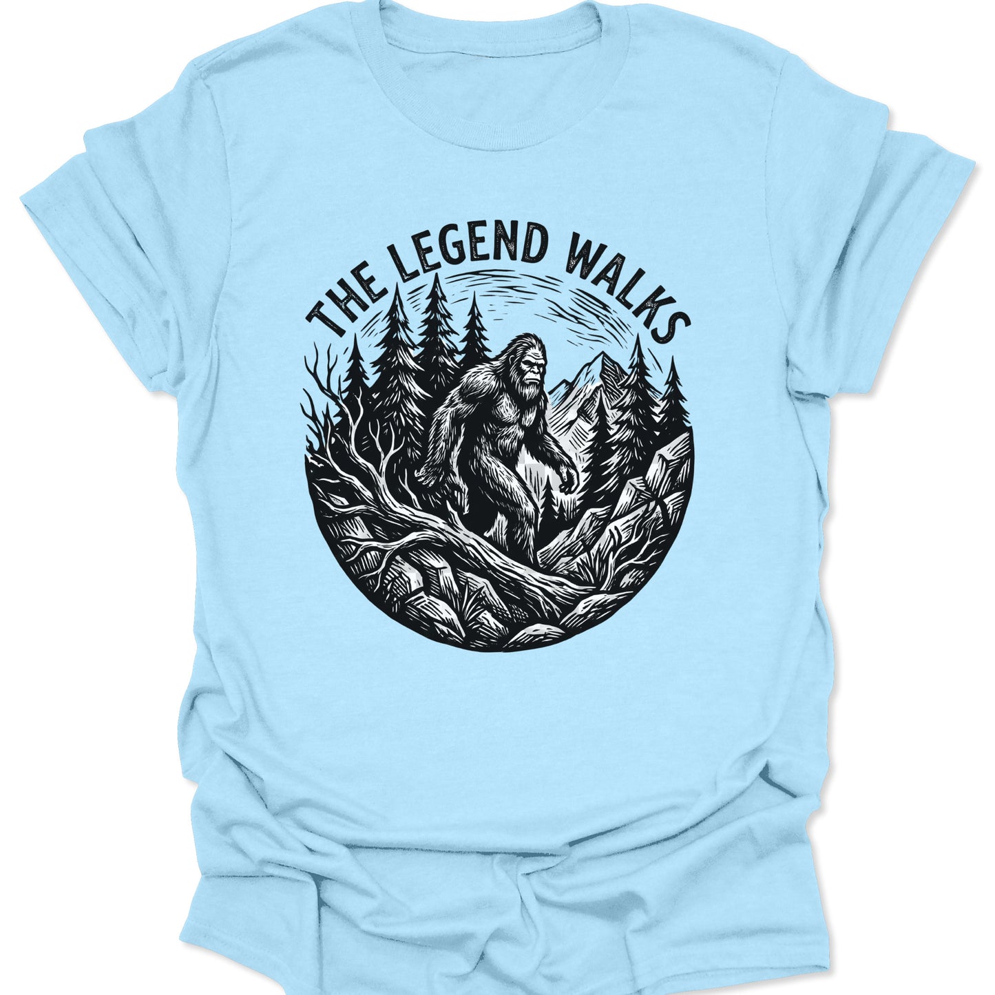 Light Blue unisex adult t-shirt featuring a black ink-style Bigfoot legend walking through a Pacific Northwest wilderness.